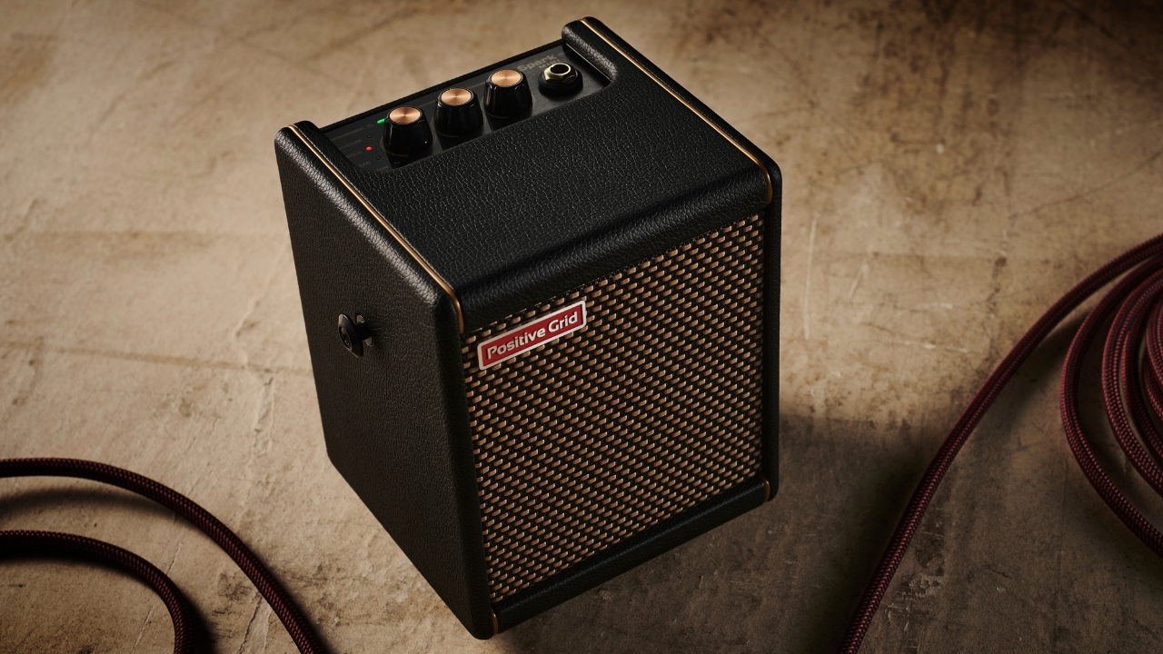 A Positive Grid Spark Mini amp on the floor with a guitar cable