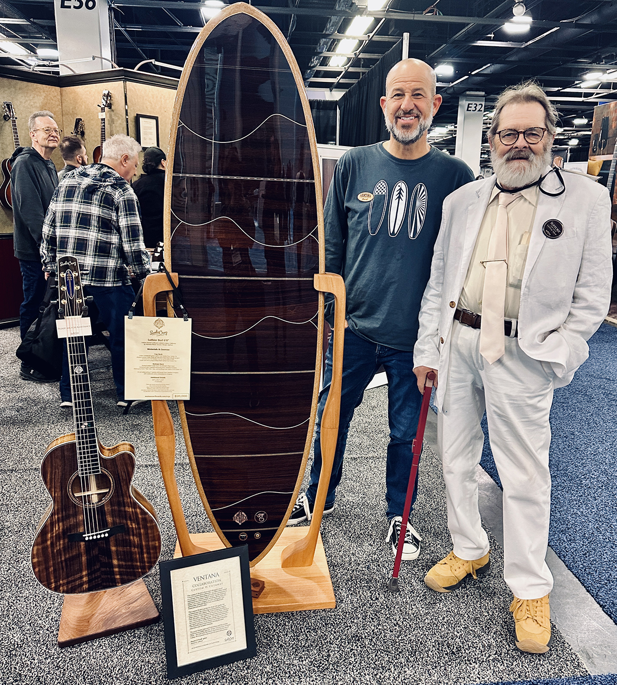 A photo of Richard Cruz (right) standing with the Santa Cruz Guitars Surfboard guitar at NAMM 2025