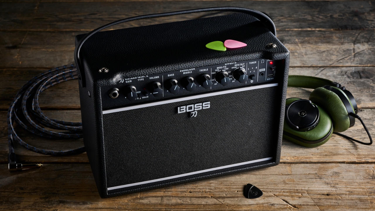 A Boss Katana Mini X guitar amp on a wooden floor with guitar picks and headphones