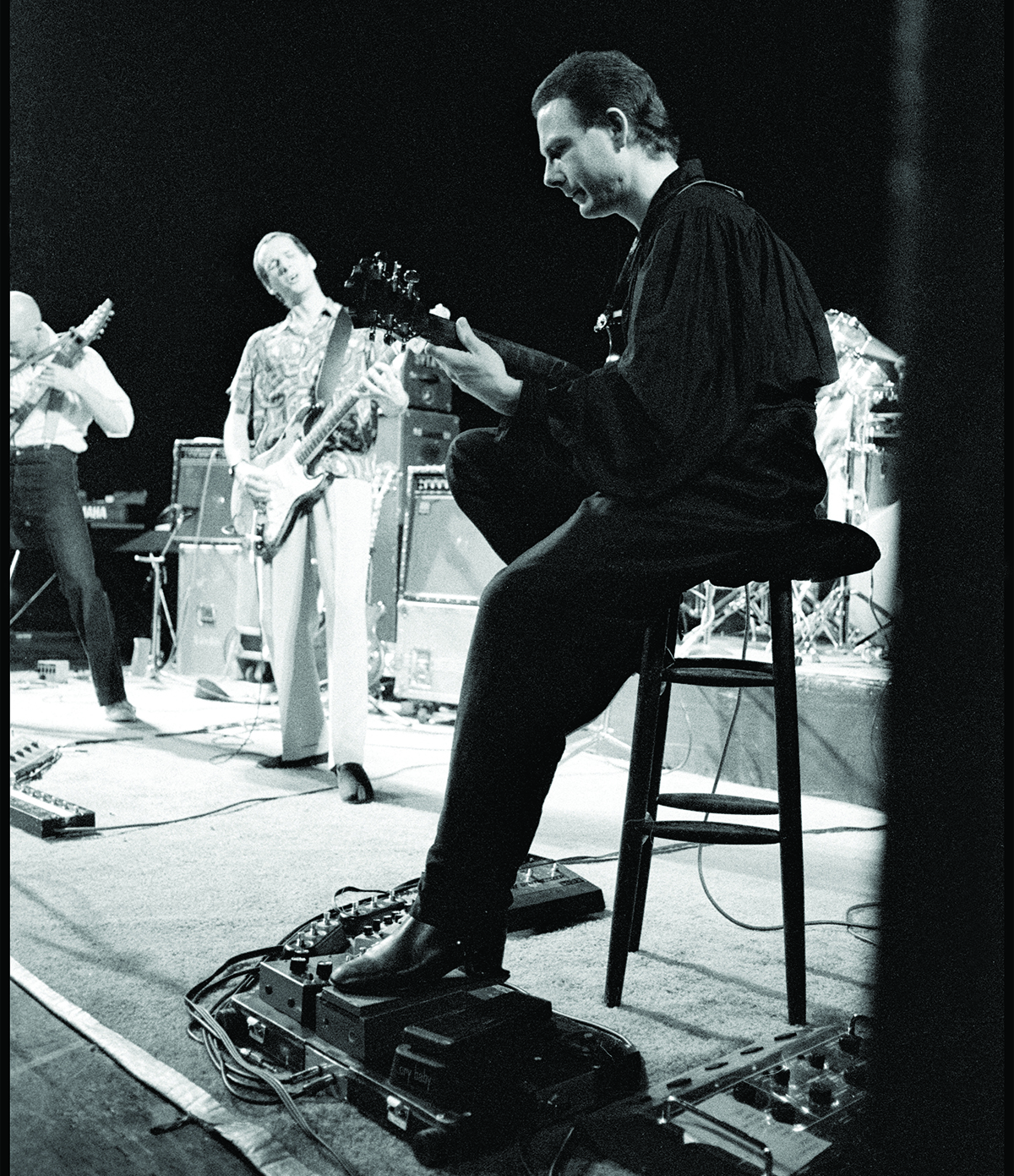 Robert Fripp (with Adrian Belew in the background) performing at Discipline Club, London, 10 May 1982.