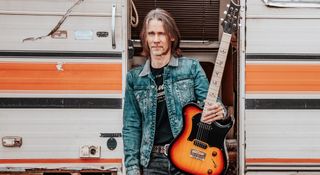 Myles Kennedy poses outdoors by a camper van with his PRS signature guitar that he used to record his new solo album, The Art Of Letting Go