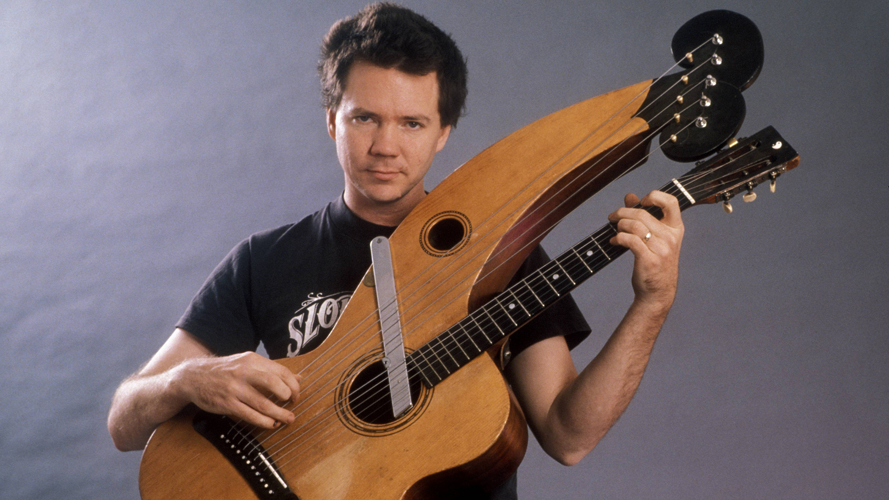 Photo of Michael HEDGES with a harp guitar in 1987