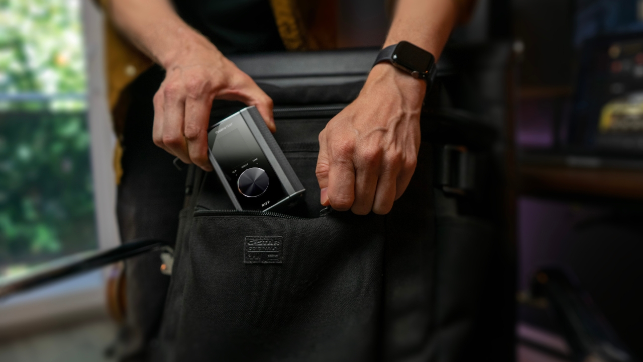 A man places a Positive Grid Riff audio interface into a bag