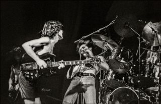 Angus Young (left) and Bon Scott perform onstage with AC/DC at the Lyceum Theatre in London on July 7, 1976