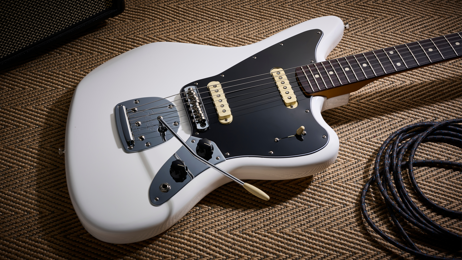 A Fender Player II Jaguar lying on the floor with a guitar cable