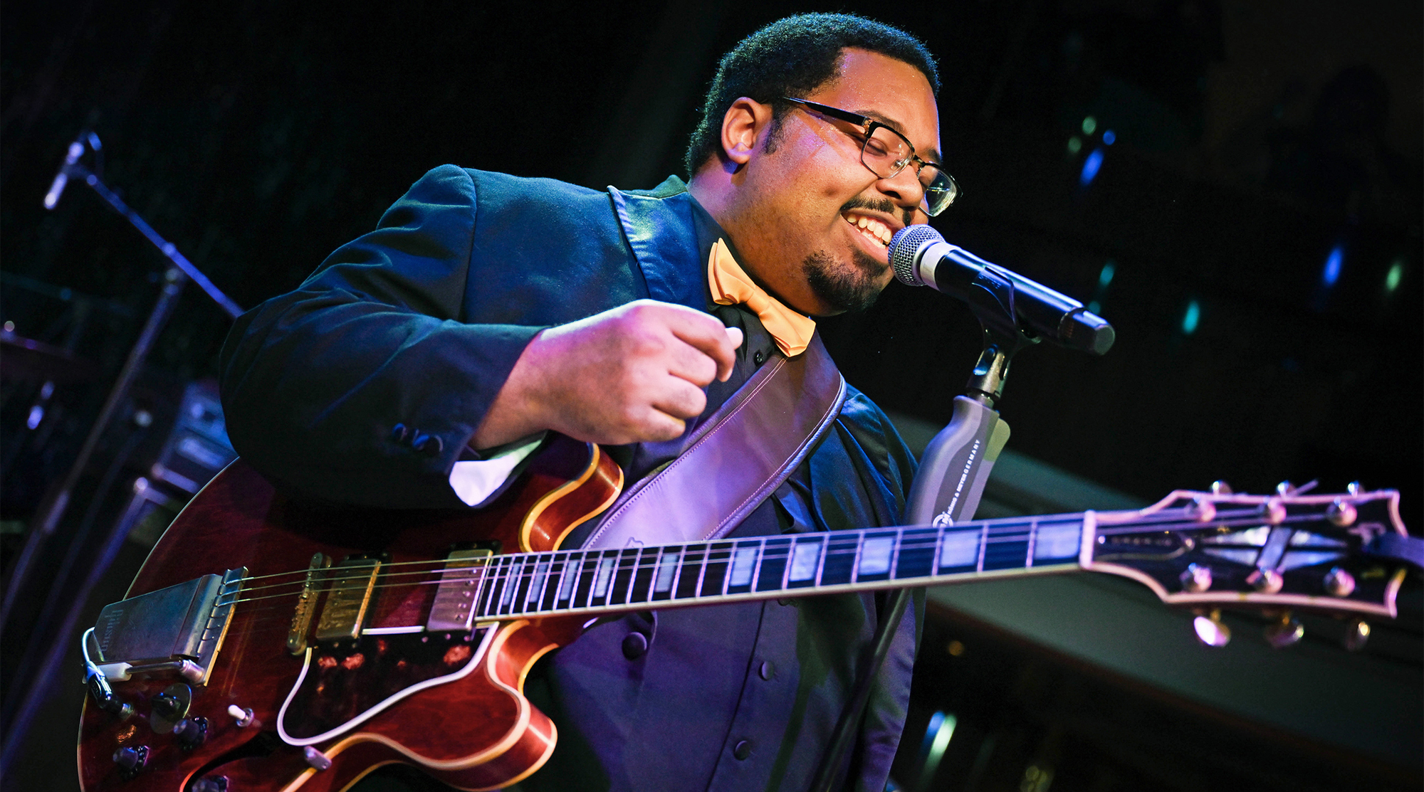 A photo of blues guitarist D.K. Harrell performing onstage with his Gibson ES-355 guitar