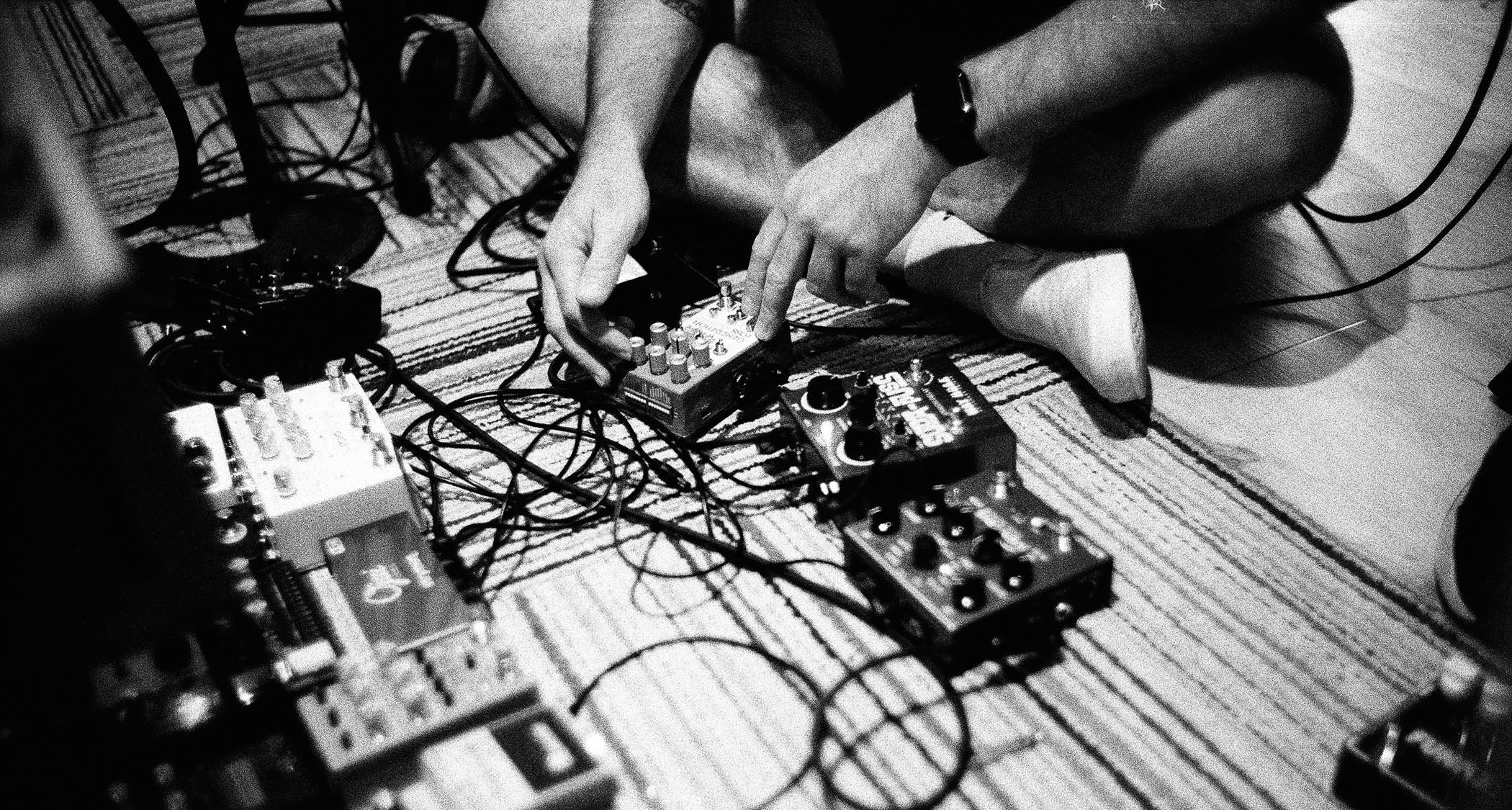 A black-and-white picture of Deafheaven experimenting with guitar pedals