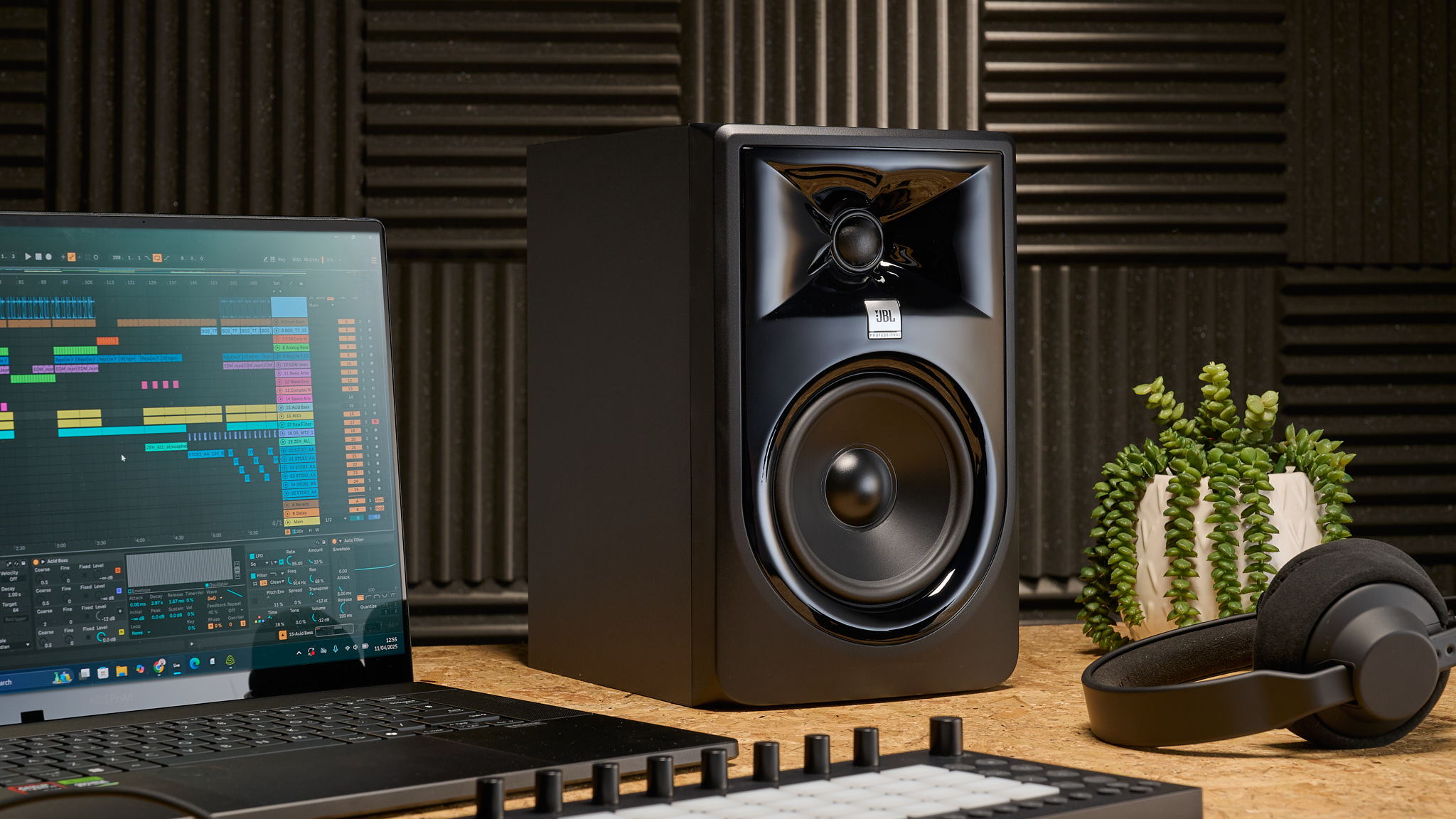 A JBL 3 Series studio monitor on a desk with a laptop and pair of headphones