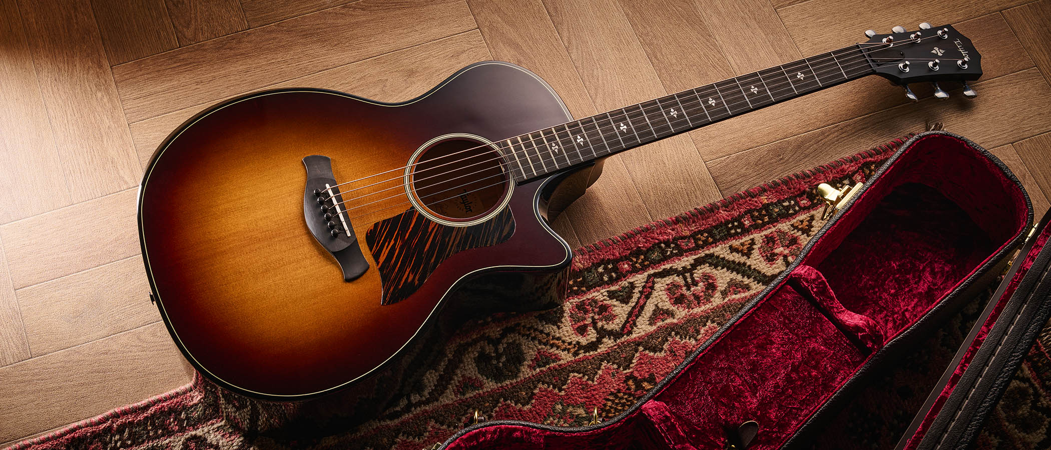 Taylor Builder&rsquo;s Edition 514ce Kona Burst pictured against a wooden floor and patterned rug.