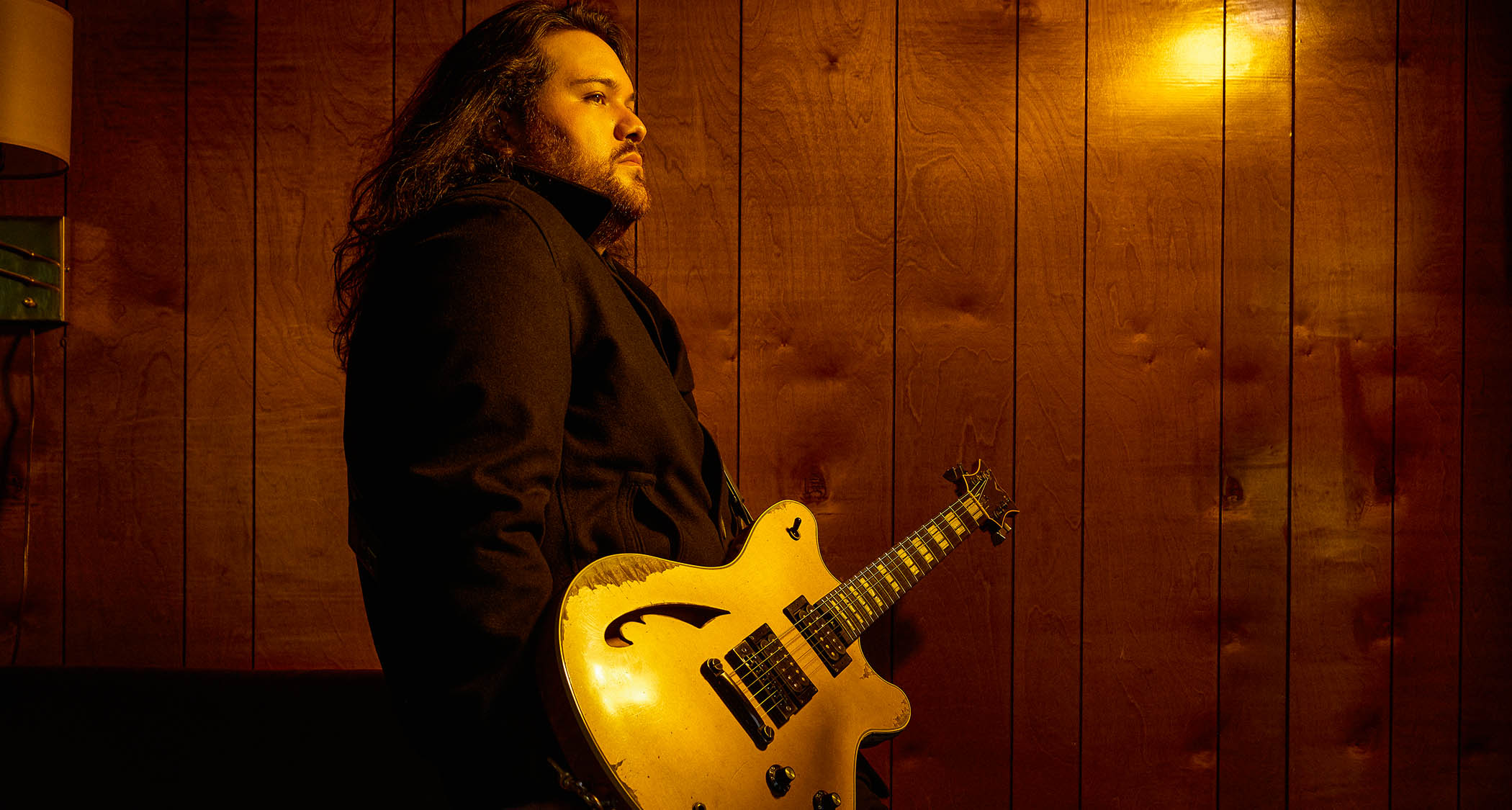 Wolfgang Van Halen pictured in warm lighting with his EVH signature semi-hollow