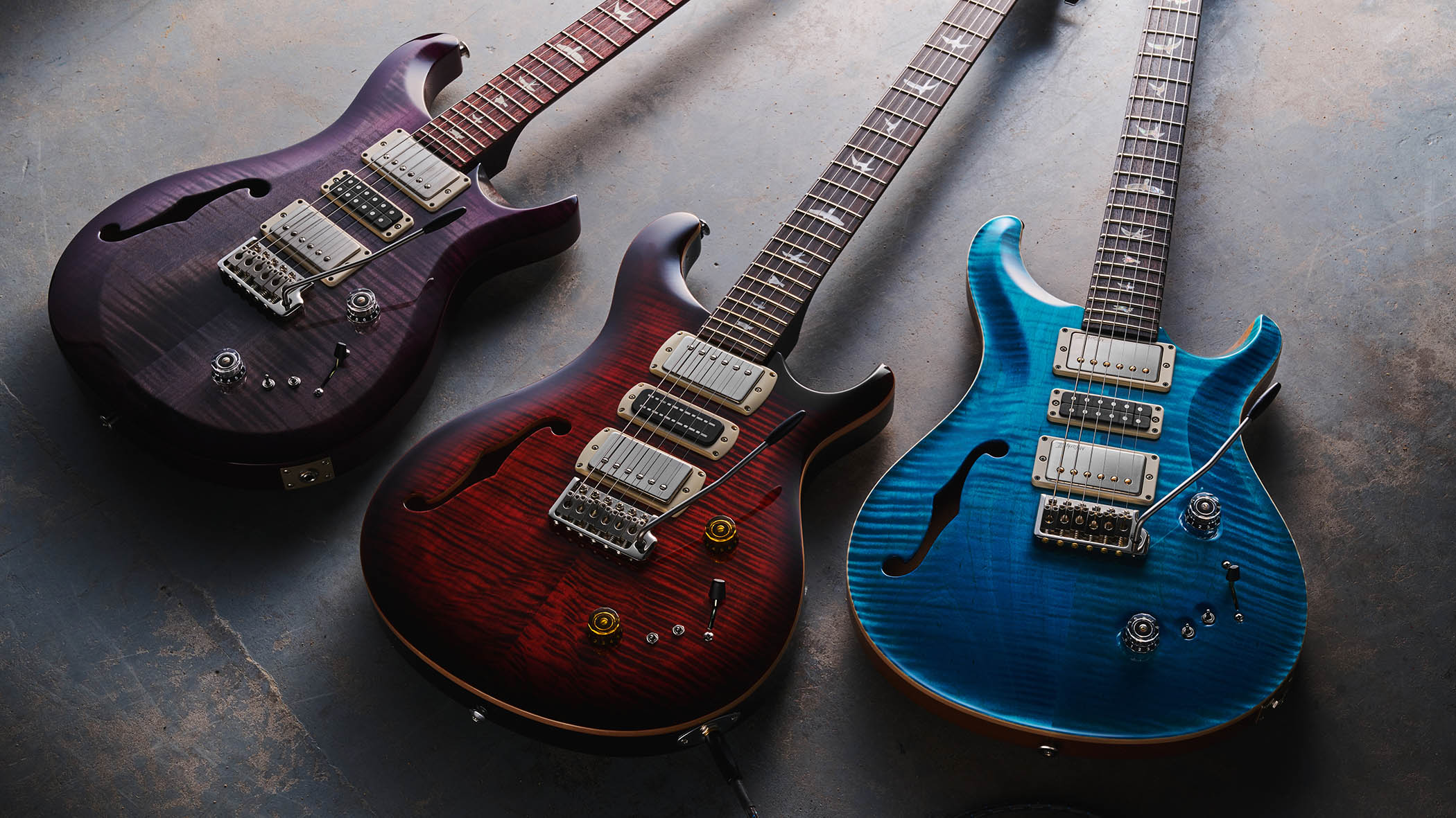 PRS Special Semi-Hollow, S2 Special Semi-Hollow and SE Special Semi-Hollow: the three figured maple-topped siblings are photographed against a grey floor.
