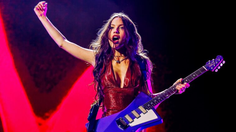 “Designed for those who love both curves and guitar: Olivia Rodrigo discusses St. Vincent's iconic model and the influence of women in rock.”]