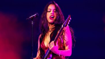 "Tailored for both comfort and style while playing guitar, Olivia Rodrigo shares her admiration for her custom Ernie Ball Music Man St. Vincent Goldie signature model."]