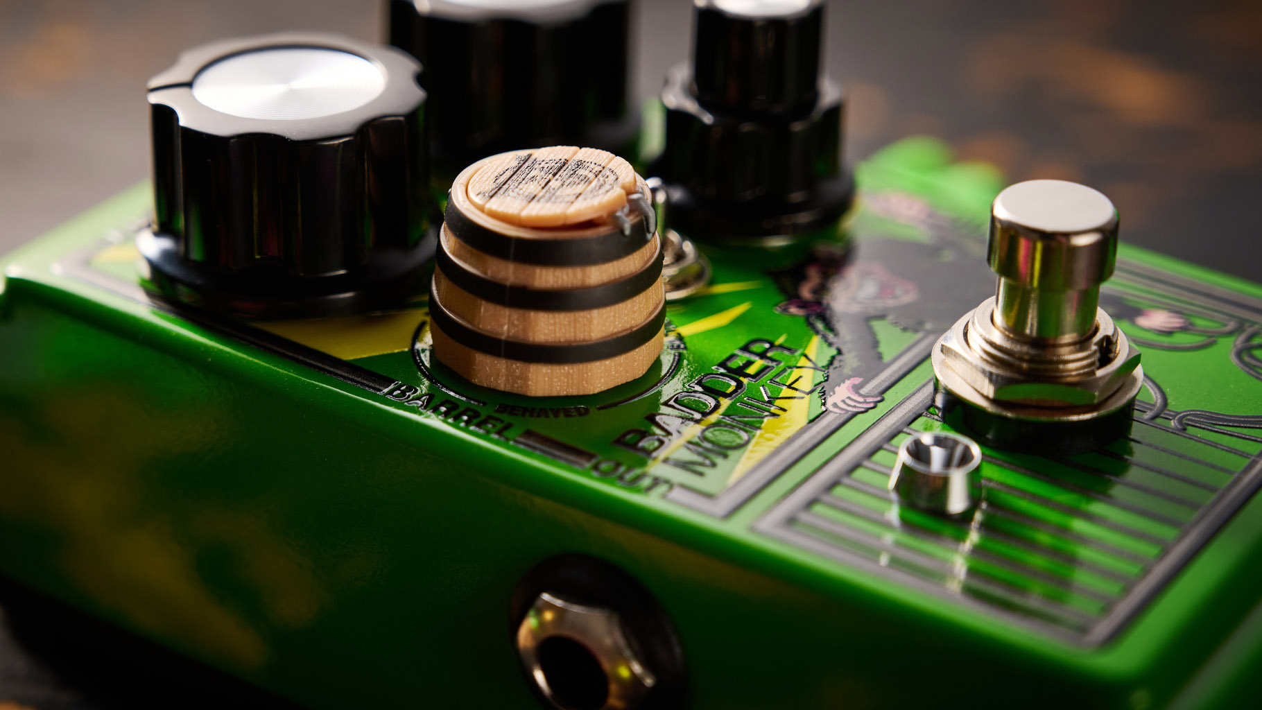 The DOD Badder Monkey is another little green overdrive pedal &ndash; but like no other. Pictured here against a distressed wooden floor, it has a wooden barrel control, and a primate illustration on the front.