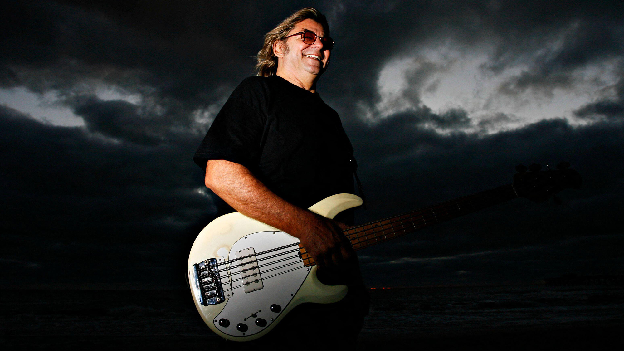 3B29BPW Nov. 12, 2009 - Largo, Florida, U.S. C CHARLIE SOUZA smiles on Redington Beach with his beloved 1988 Musicman Stingray five-string bass, that he says has over 200,000 miles on it. This weekend the local rocker and his band The Tropics will perform their song ''Carry me back to St. Petersburg,'' at Ribfest after it was chosen earlier this fall as the city's new theme tune.