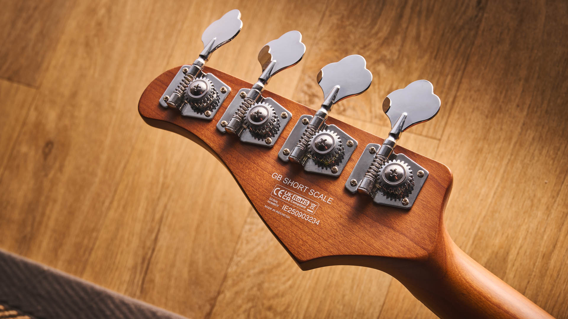 The Cort GB-Short Scale Bass finished in green, photographed against a light wooden floor and rug.