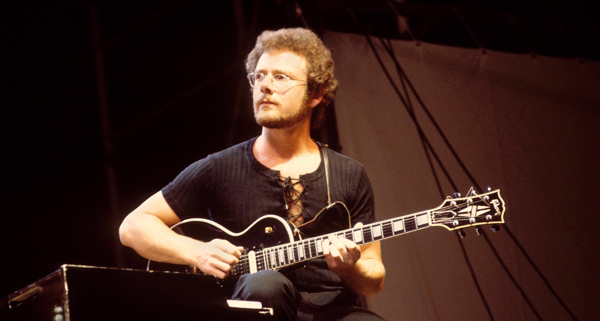Robert Fripp wears a black lace-up T-shirt and plays his Gibson Les Paul Custom with King Crimson in 1974