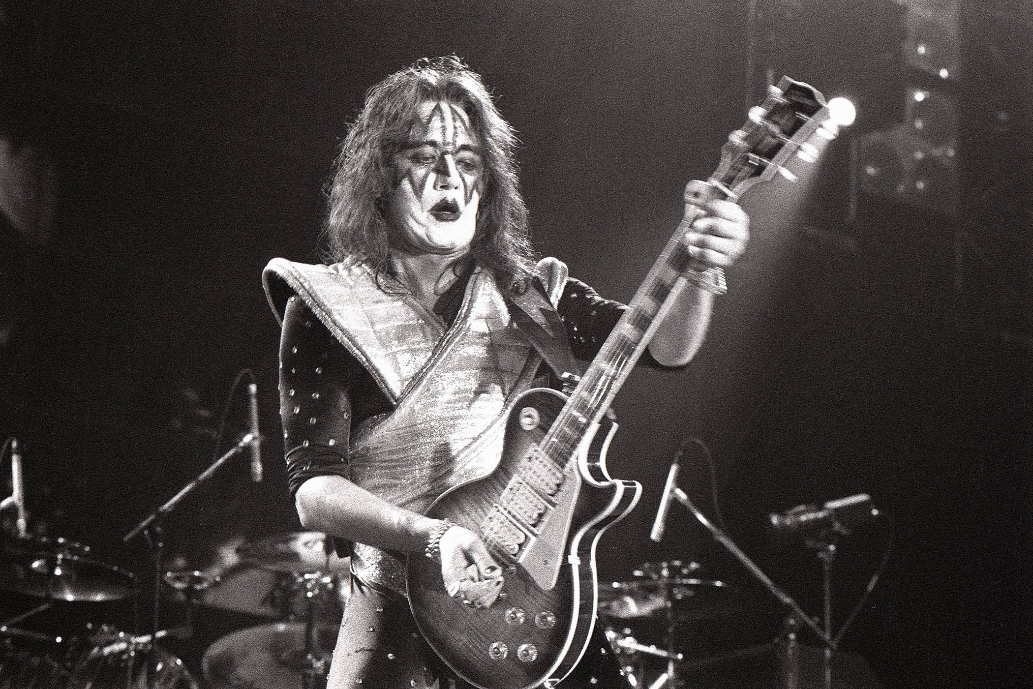 A black-and-white shot of Ace Frehley performing with his triple-humbucker "Budokan" Les Paul in 1977