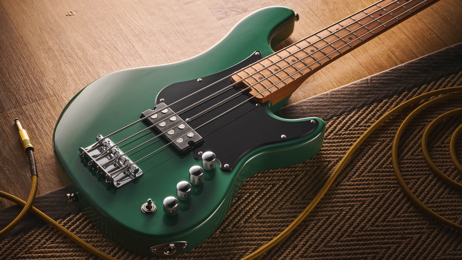 The Cort GB-Short Scale Bass finished in green, photographed against a light wooden floor and rug.
