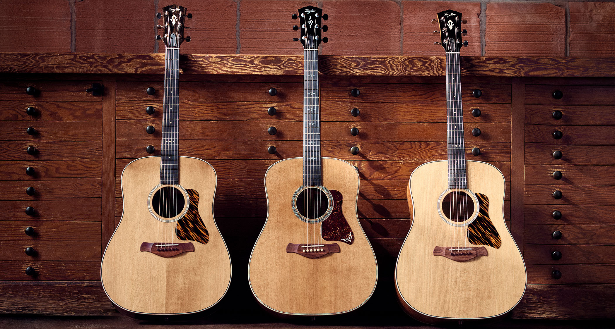 The Taylor Gold Label 510e, Gold Label 710e and 810e are photographed together against a wooden set of drawers.