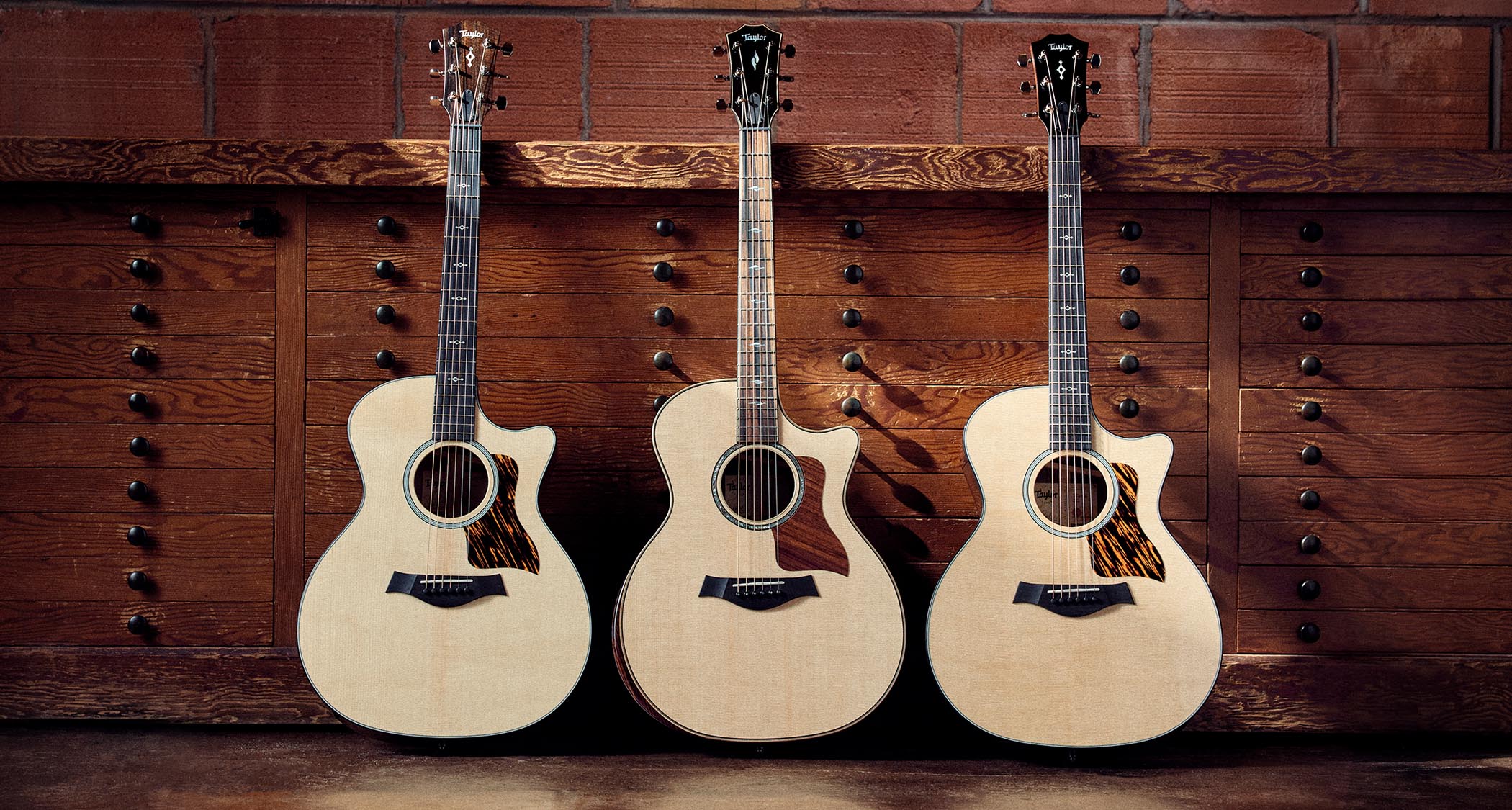 Three of Taylor's Next Generation Grand Auditorium acoustic guitars photographed in profile.