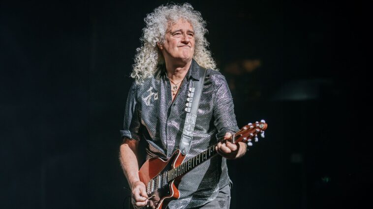 Brian May describes America as "too risky" for Queen's comeback.]