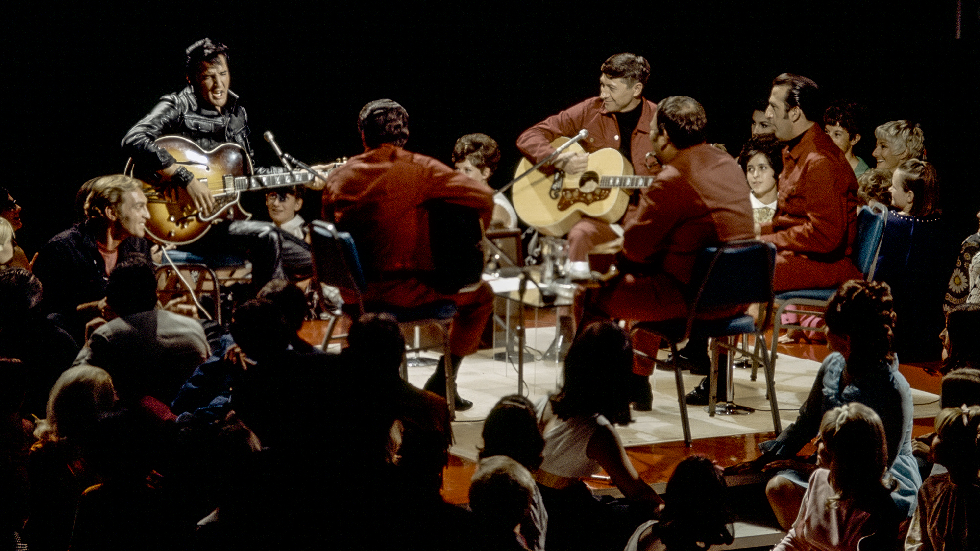 ELVIS: '68 COMEBACK SPECIAL -- Aired 12/3/68 -- Pictured: Elvis Presley during a performance at NBC Studios in Burbank, CA. Scotty Moore, Elvis's first guitarist, is seated opposite him on the right playing an acoustic guitar