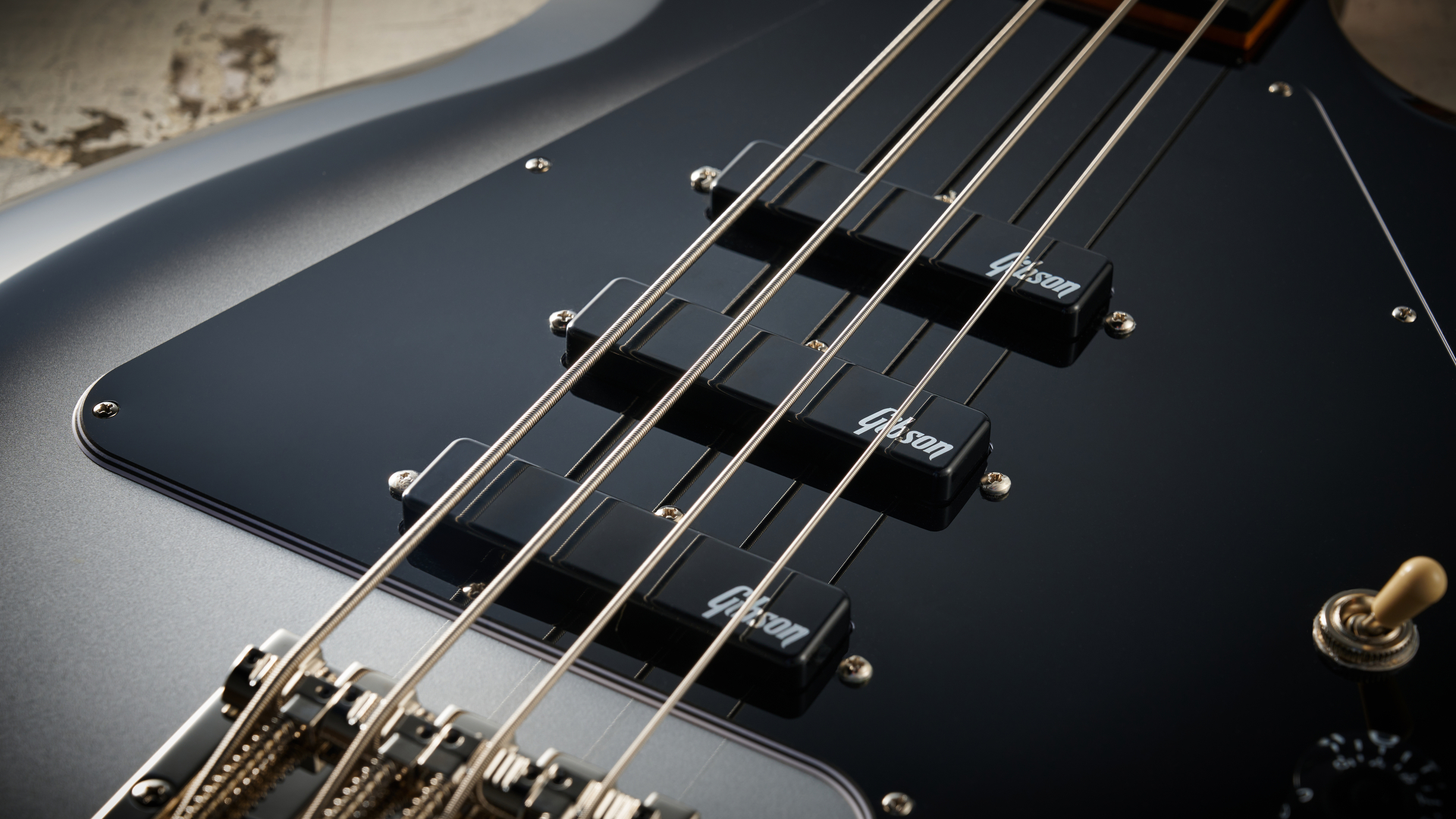 Epiphone Mike Dirnt Grabber G-3 in Silverburst finish photographed on scratched white board.