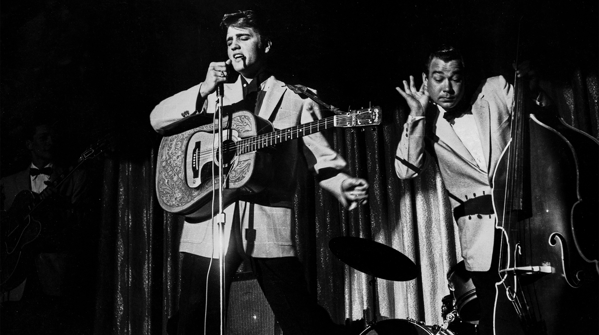 American actor and singer Elvis Presley singing on stage with musician Bill Block, circa 1950s.