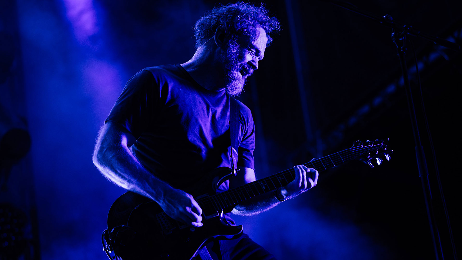 Karnivool guitarist Mark Hosking plays his PRS guitar onstage under a purple light