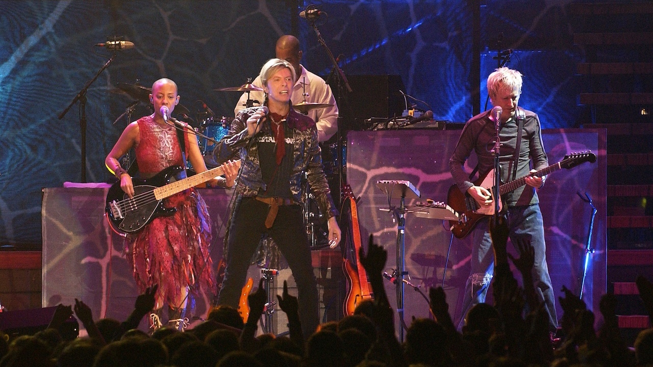 David Bowie (C) performs on stage at the Bercy Stadium in Paris on October 20, 2003. At left, Gail Ann Dorsey