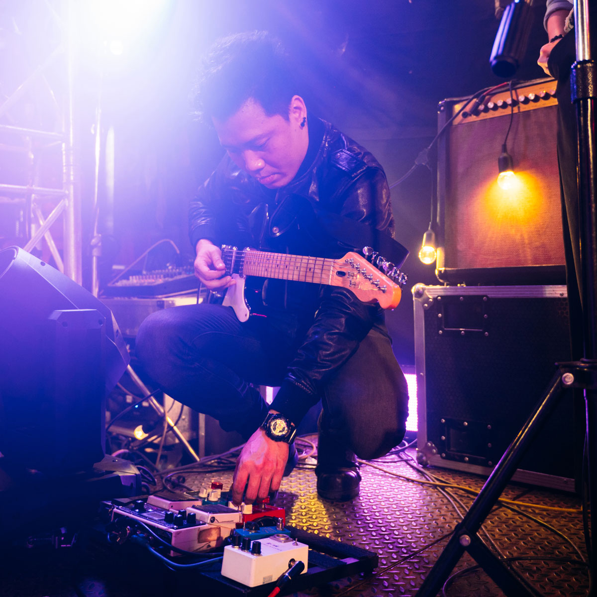 A guitarist checks his pedals