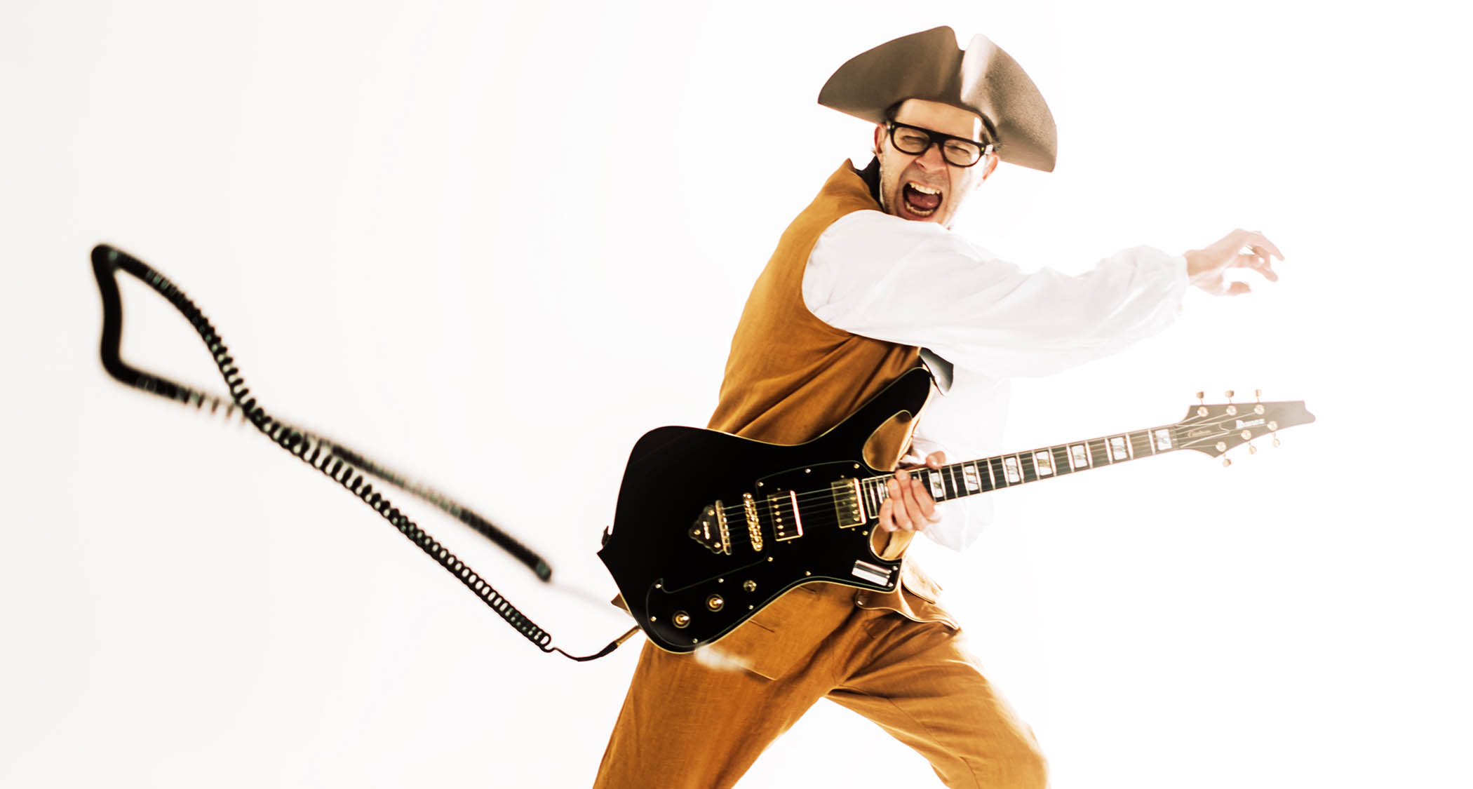 Paul Gilbert wears a tricorn hat and plays his hot-pink Ibanez signature model