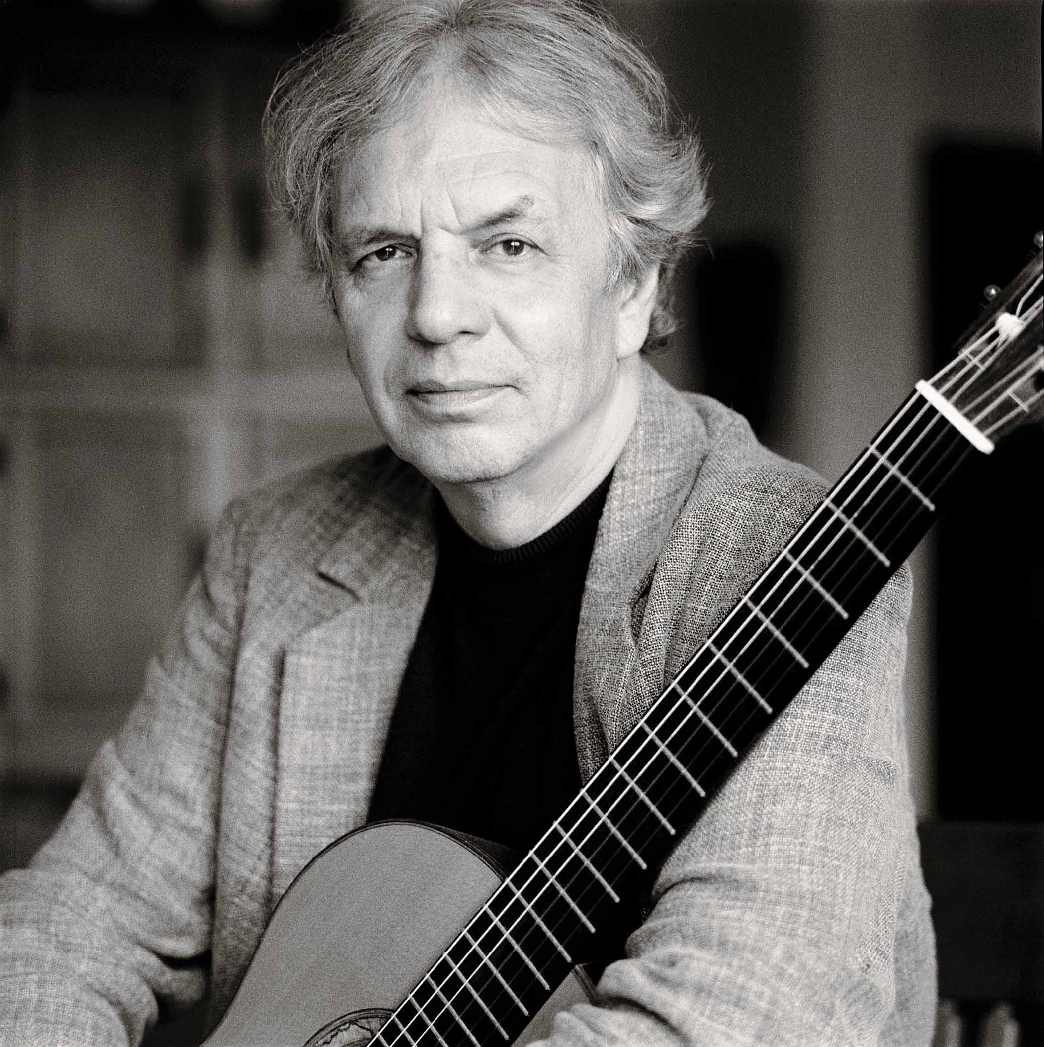 A black-and-white portrait of Ralph Towner with his acoustic guitar