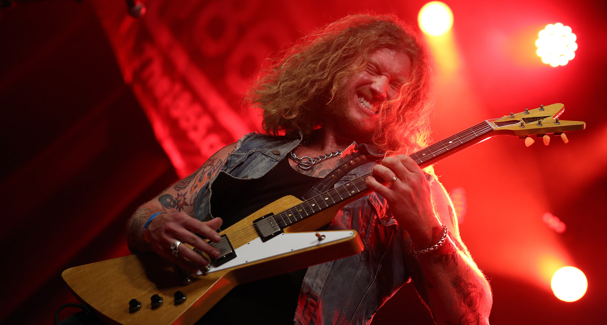 Jared James Nichols plays a Gibson Futura on a stage bathed in red lights.